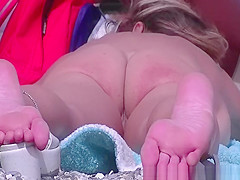 Nudist woman laid down on her abdomen sunbathing