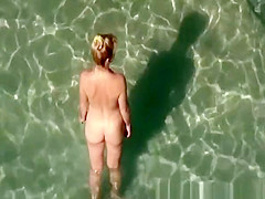 Nudist woman takes off her dark bikini