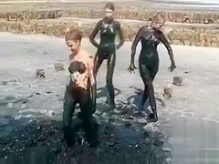 Youthful ladies coat their bodies in black mud
