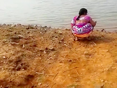 Indian woman peeing in the foul by a lake