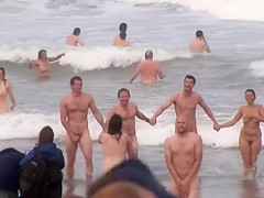 Hundreds of nudist people running into the sea stripped
