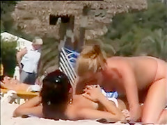 Deux copines topless simulent de baiser sur la plage